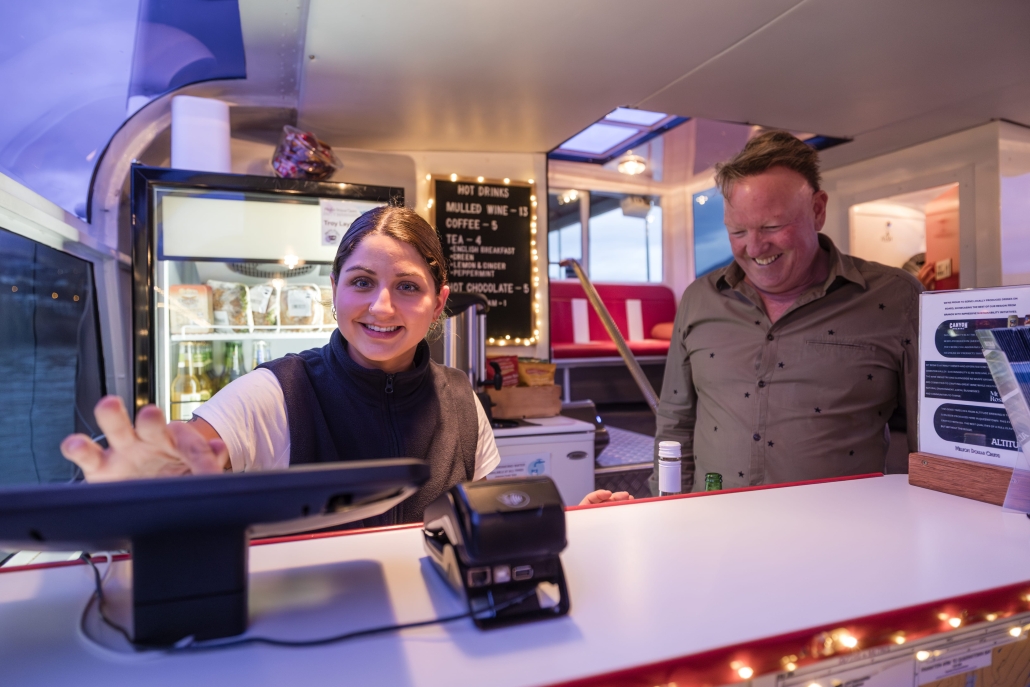 BrookedV_MDC_May25-9-min Smiling cashier serving a happy customer on a cruise.